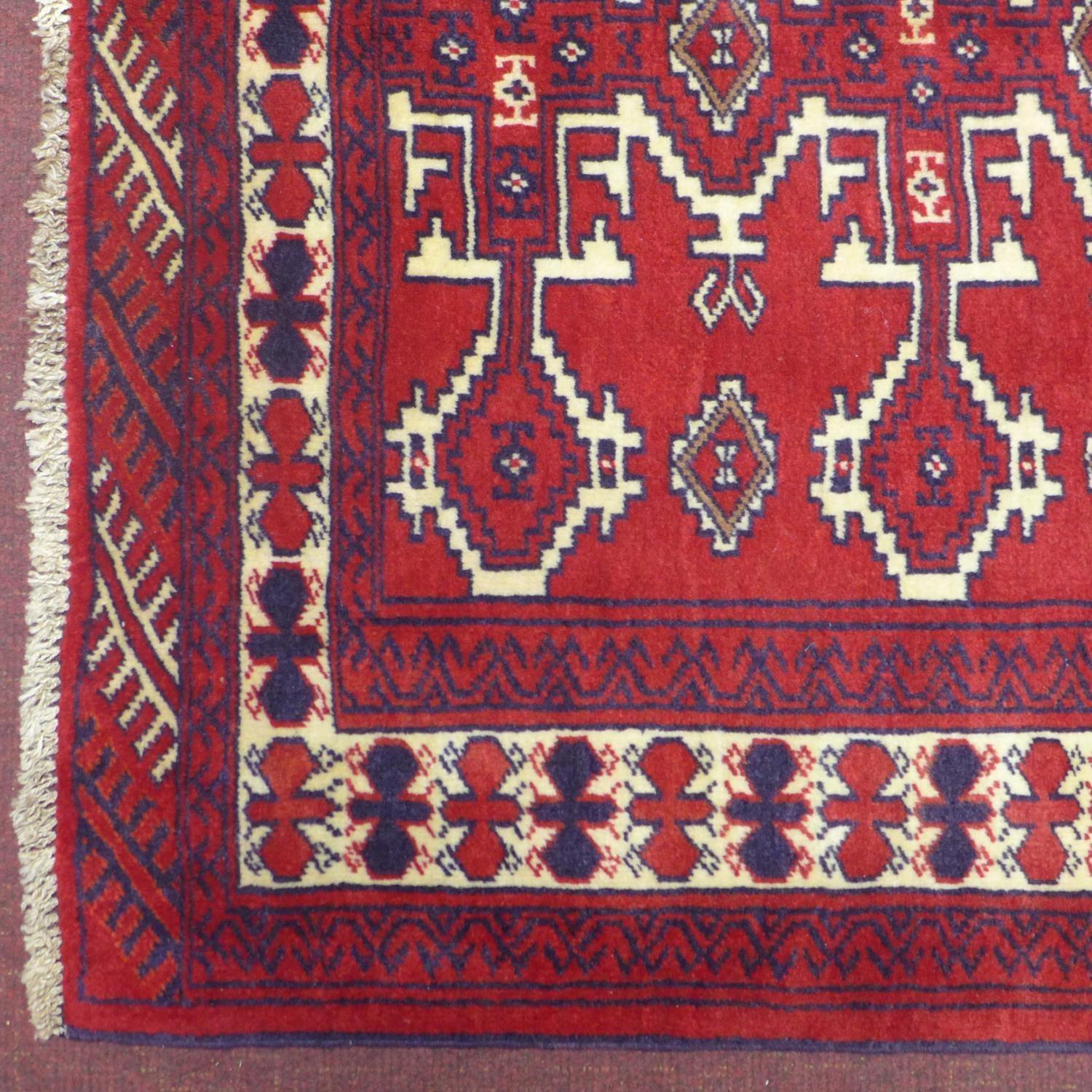 A north east Persian Yamut rug, with repeating stylized gull motifs, on a rouge field, within - Image 2 of 3