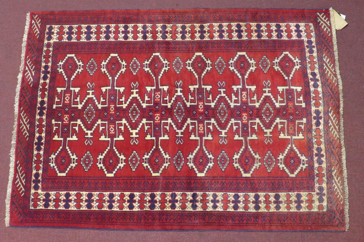 A north east Persian Yamut rug, with repeating stylized gull motifs, on a rouge field, within