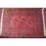 A 20th century Bokhara rug with triple gull motifs, on a red & black ground, contained by