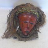 A 19th century red lacquered African Tribal mask, with hair and hood