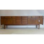 A mid 20th century teak sideboard with 3 central drawers, flanked by 4 drawers and 4 cupboard doors,
