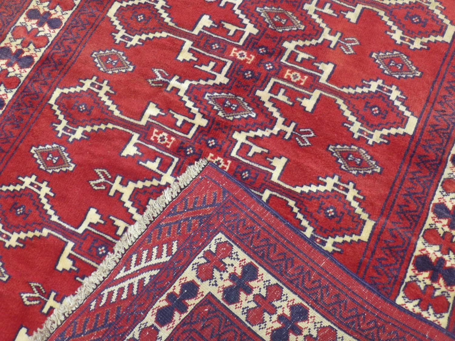 A north east Persian Yamut rug, with repeating stylized gull motifs, on a rouge field, within - Image 3 of 3