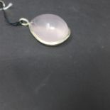 A large sterling silver pendant set with a tear-drop shaped polished rose quart cabochon to a silver