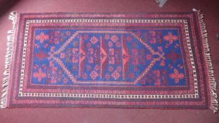 A 20th century Turkish Yagcibedir rug with geometric design, on a red and blue ground, contained by