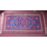 A 20th century Turkish Yagcibedir rug with geometric design, on a red and blue ground, contained by