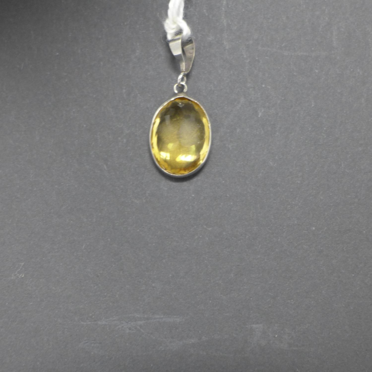 A 14ct white gold pendant set with an oval, faceted natural citrine to a white gold pendant loop,
