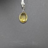 A 14ct white gold pendant set with an oval, faceted natural citrine to a white gold pendant loop,