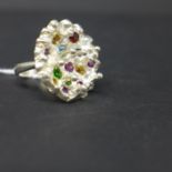A sterling silver ring in the form of a flower head with stamens set with garnet, pink and blue