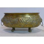 An oval brass planter, repousee embossed with grape vines, having lion head ring handles, on claw