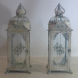 A pair of contemporary distressed white painted storm lanterns, raised on lion paw feet, H.73cm