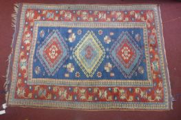 A 20th century Turkish rug with 3 geometric medallions, on a blue ground, contained by blue ground