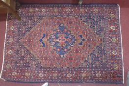 An antique Senneh rug with geometric medallion, surrounded by motifs, on a red and blue ground,