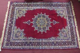 An antique Kirman rug with floral medallion, on a red ground, contained by floral border, 213 x