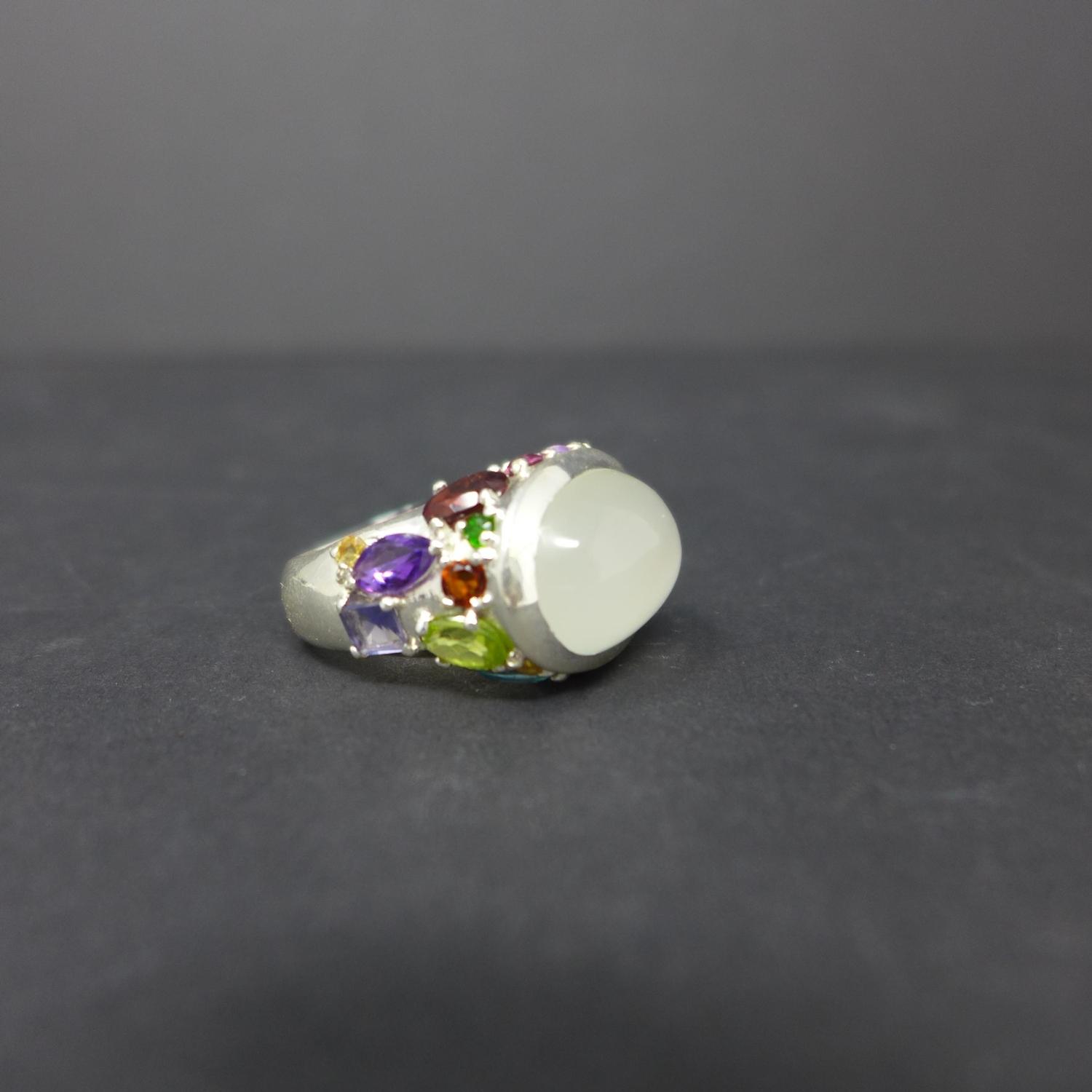 A sterling silver and moonstone ring set to the side of the mount with precious and semi-precious