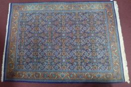 A mid 20th century part silk Tabriz rug, with repeating geometric floral motifs, on a blue ground,