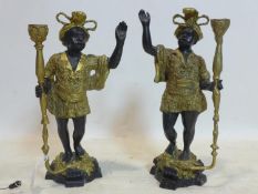 A pair of cast metal Blackamoor candlesticks, in elaborate dress and plumed turbans and holding