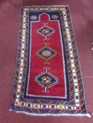 A 20th century Shirvan rug, with 3 geometric medallions on a red ground, contained by geometric