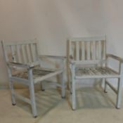 A pair of weathered teak garden armchairs