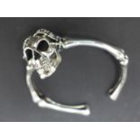 A silver skull and bones bangle, W.7cm