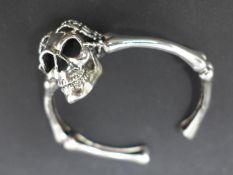 A silver skull and bones bangle, W.7cm