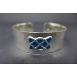 A Celtic style white metal and enamel bangle