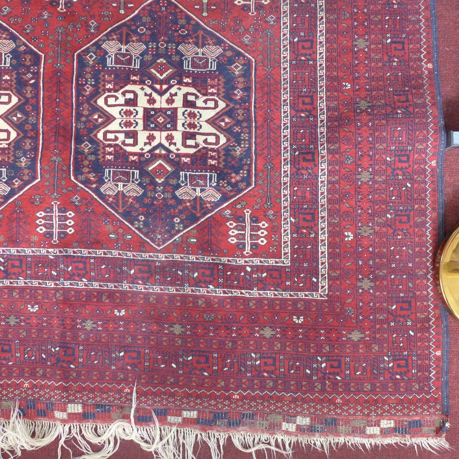 A 20th century Afghan carpet with 6 geometric medallions, on a red ground, contained by many - Image 2 of 3