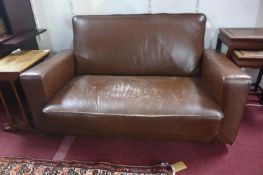 An early to mid 20th century brown leather sofa, raised on castors