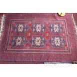 A 20th century Afghan carpet with 6 geometric medallions, on a red ground, contained by many