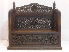 A 19th century Burmese bench, deeply carved and pierced with figures and mythical beats, with hinged