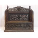 A 19th century Burmese bench, deeply carved and pierced with figures and mythical beats, with hinged