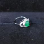 An Art Deco style white gold ring set with jade cabochon surrounded by diamonds