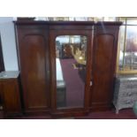 A Victorian mahogany triple wardrobe with central mirrored door flanked by 2 cupboard doors,