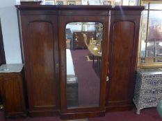 A Victorian mahogany triple wardrobe with central mirrored door flanked by 2 cupboard doors,