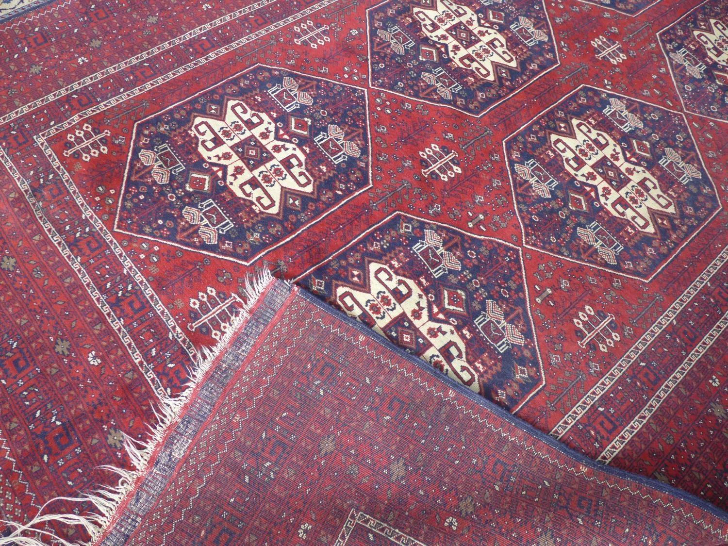 A 20th century Afghan carpet with 6 geometric medallions, on a red ground, contained by many - Image 3 of 3