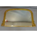 A mid 19th century gilt arched overmantle mirror with carved decorated frame. H.92 W.154cm