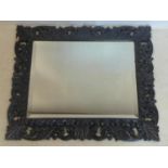An early 20th century thick carved oak mirror with beveled plate, 86 x 100cm