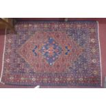 An antique Senneh rug with geometric medallion, surrounded by motifs, on a red and blue ground,