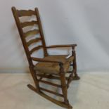 A 19th century oak ladder back rocking chair with original rush seat