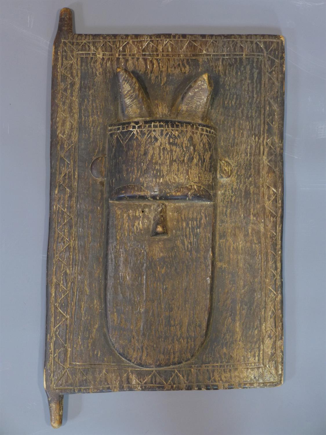 An antique African tribal art door panel, carved with a mask, possibly Dogon tribe, Mali, 52 x 34cm