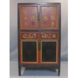 A late 19th century Chinese black and red lacquered wedding cabinet, with two doors carved with