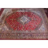 A large Persian carpet, with central floral medallion and floral motifs on a red ground, within