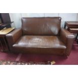 An early to mid 20th century brown leather sofa, raised on castors
