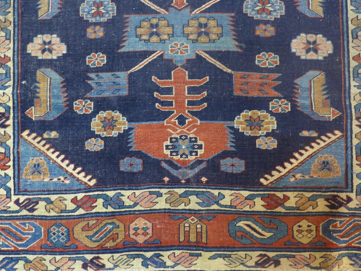 A Caucasian rug with geometric and floral motifs on a dark blue ground, within stylised floral - Image 3 of 5