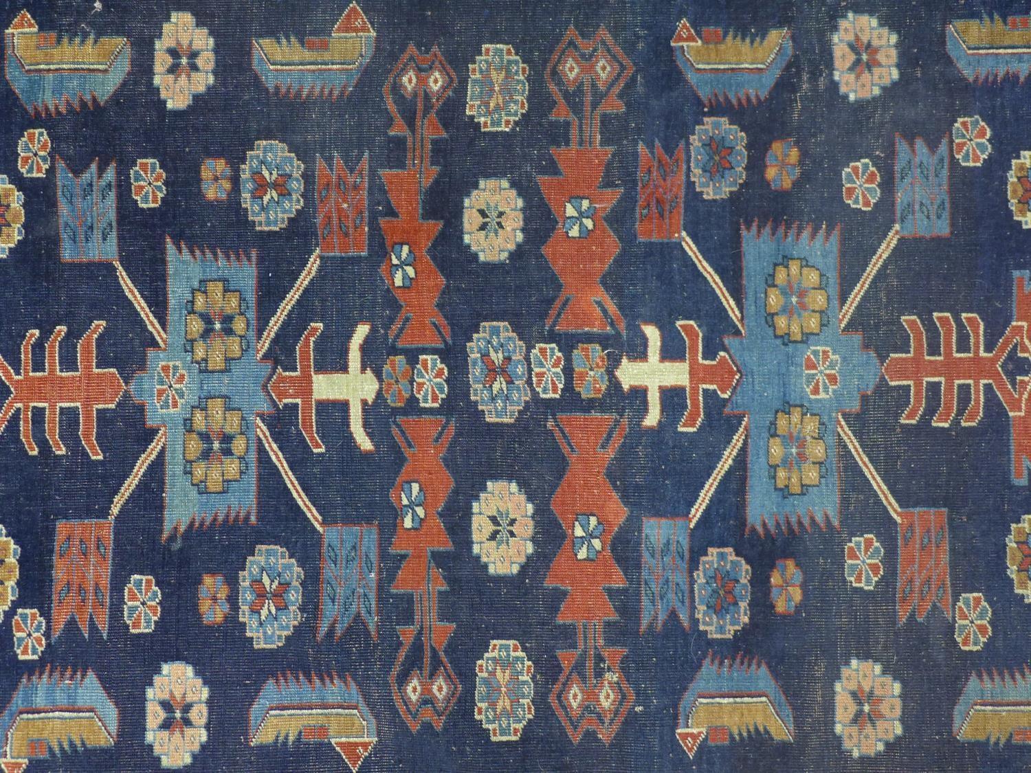 A Caucasian rug with geometric and floral motifs on a dark blue ground, within stylised floral - Image 2 of 5
