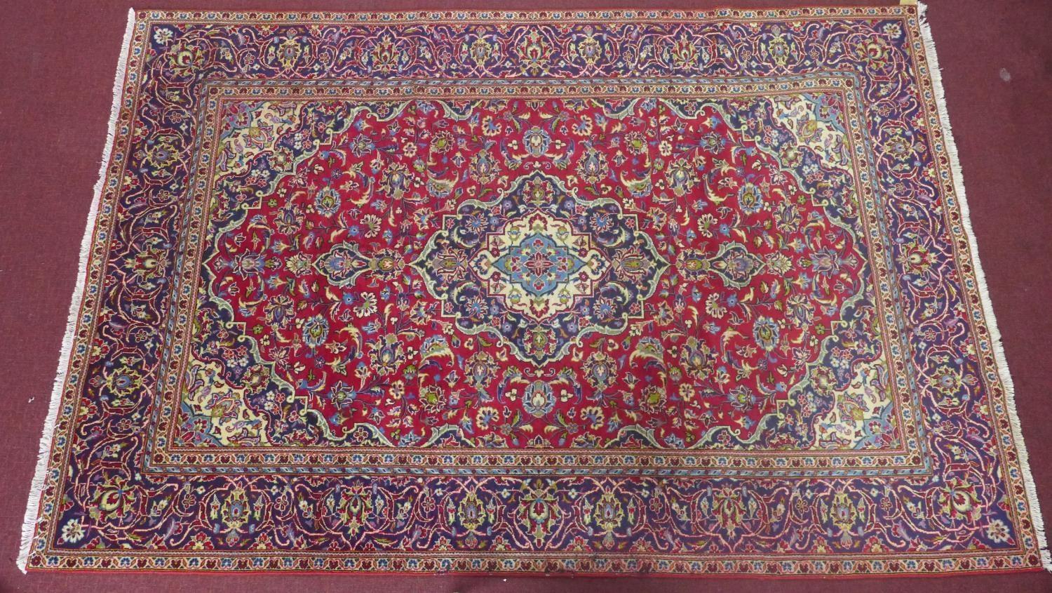 a central Persian Kashan carpet, the central double medallion with repeating petal motifs on a rouge