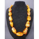 A amber necklace of 21 beads in its retail case. L.60cm