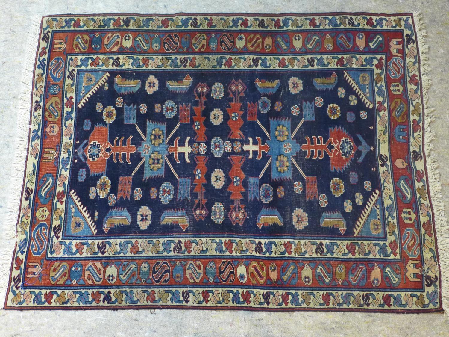 A Caucasian rug with geometric and floral motifs on a dark blue ground, within stylised floral