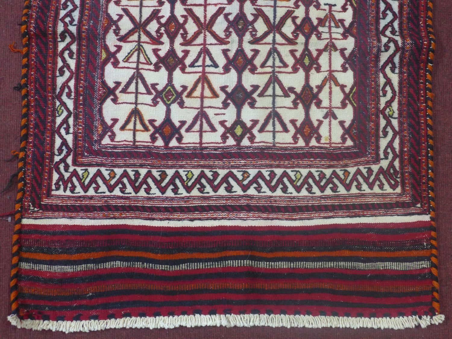 A north east Persian Sumak kelim with repeating stylised geometric motifs on a rouge field. L.120 - Image 3 of 4