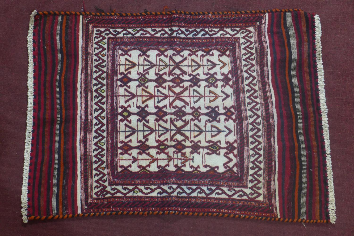 A north east Persian Sumak kelim with repeating stylised geometric motifs on a rouge field. L.120