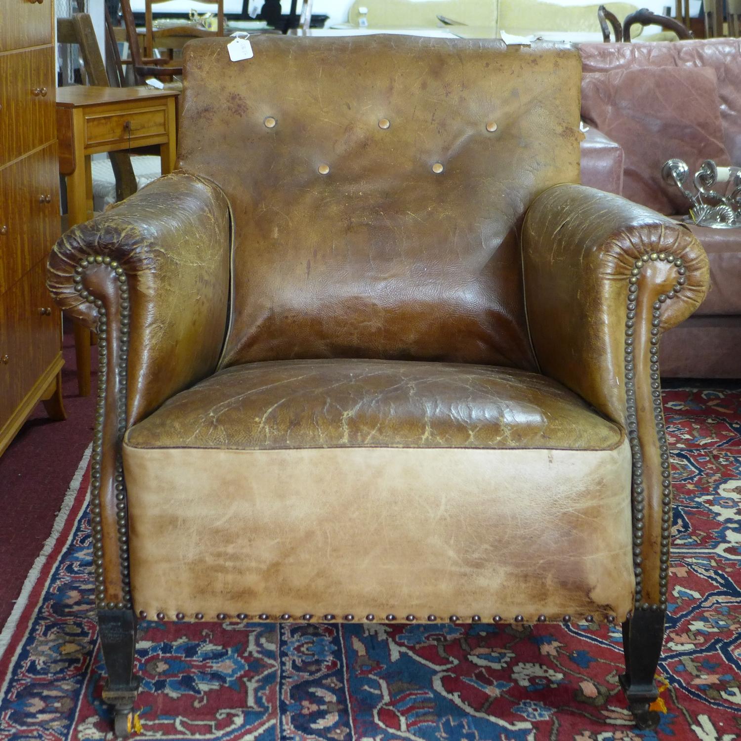 A 20th century stud bound brown leather club armchair, H.83 W.84cm, heavily worn, with cracks to